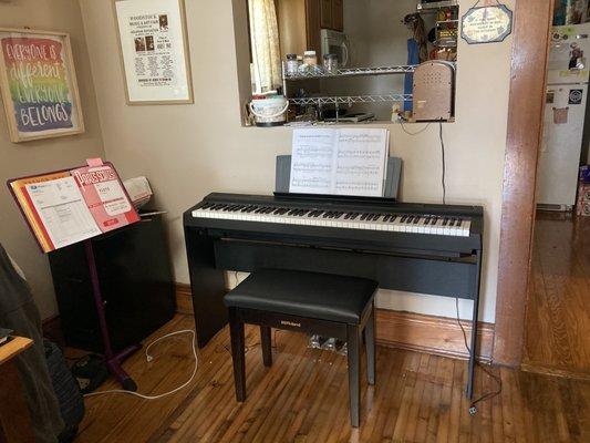 Yamaha digital piano with wooden legs, full pedal set-up, and a Roland rosewood piano bench with hidden cabinet inside