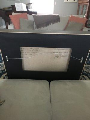 Plastic window on the back of a frame so you can read the painter's hand written note