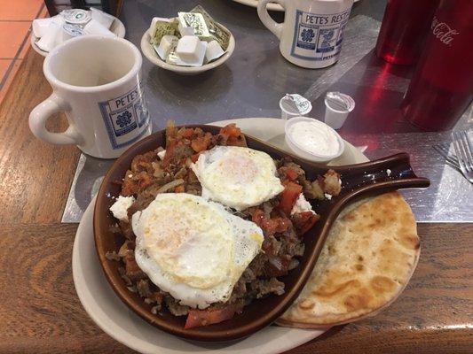 Greek Skillet with two eggs over easy and pita bread.