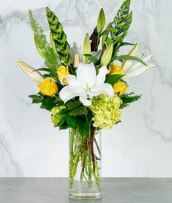 Inez - Make a statement with this tall and showy yellow roses and white lily arrangement designed in a tall clear glass cylinder.