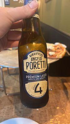 Poretti beer with pizza in the background.