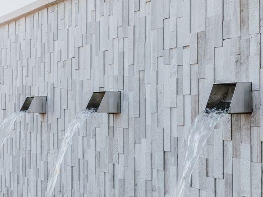 Custom water feature with square stainless steel spouts; natural ledger panels stacked stone laid vertically