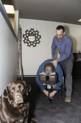 Dr. Sam adjusting a patient and getting some support from Nugget, the office mascot!