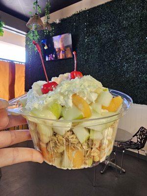 Fruit Salad - Pear, apple, mango, banana with ice cream in the middle topped with granola whip cream and cherry on top.