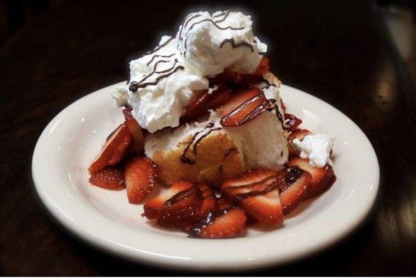 Angel food cake topped with fresh strawberries and coconut whip cream