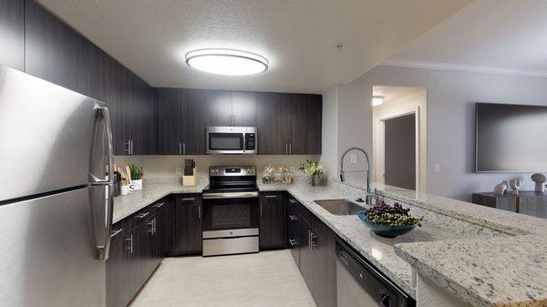 Spacious kitchen featuring hardwood-style vinyl floors, granite countertops, and stainless steel appliances.