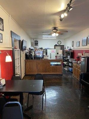 The front desk of the cafe features a coffee machine and several tables