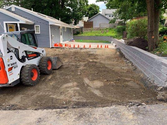 Retaining wall, patio, driveway asphalt, walkway pavers, and fence.