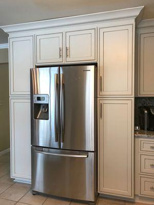 Refrigerator flanked by two custom pantries. Painted & glazed cabinetry.