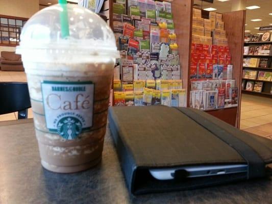 Reading and enjoying a frappuccino.