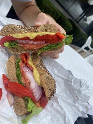 Whole wheat everything bagel with lettuce, tomato, onion, roasted peppers, and yellow mustard.