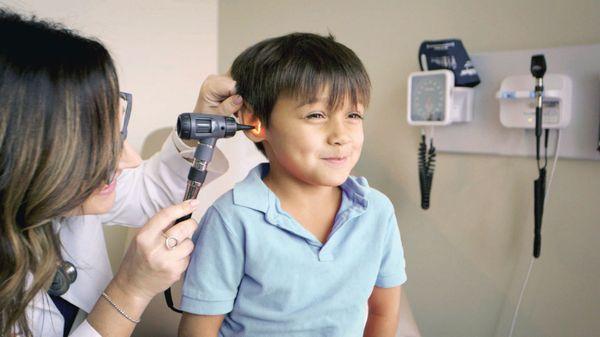 Summer Carlson examining the ear canal of a young boy.