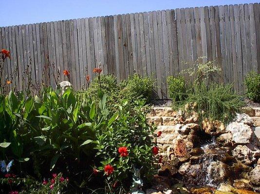 What's better than gorgeous flowers and plants brightening up your backyard? Adding a stone fountain, like we did here (on the right)!