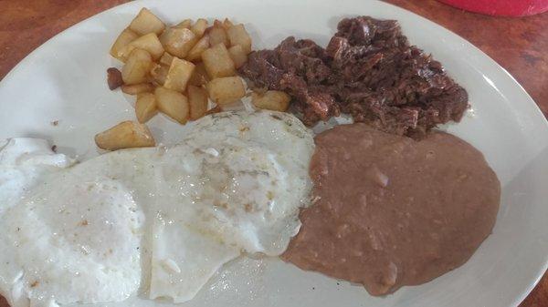 Barbacoa, eggs, potatoes, and refried beans.