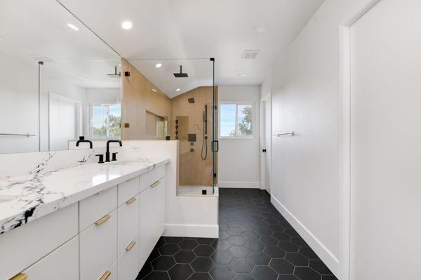 Elegant bathroom featuring a spa-like walk-in shower, dual vanity with marble countertops, modern fixtures, and stylish hexagonal flooring.