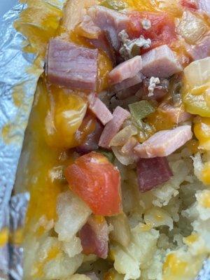 What kind of baked potato has lunch meat and some white onions and tomatoes and peppers? Where is the bacon and green chives and sour cream?