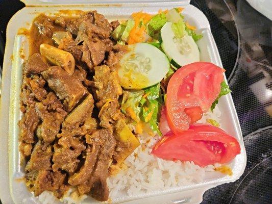 Medium curry goat with white rice and salad. It was very flavorful and had a nice kick to it.