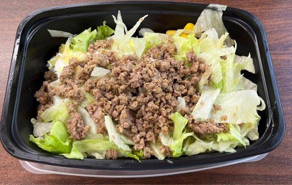 Bowl with white rice and "steak". It also has black beans, corn, iceberg lettuce, salsa, and avocado.