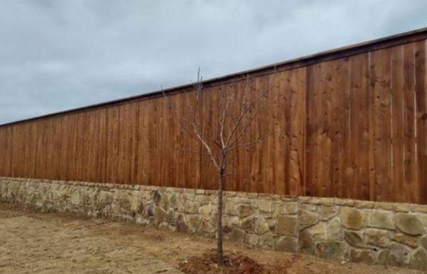 Rock retaining wall with cedar fence an top board