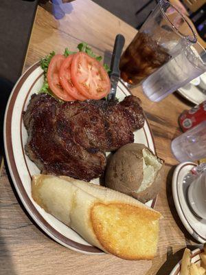 Ribeye steak, baked potato and toasted bread