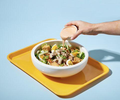 Thai chef's salad with lettuce, chicken, egg, cucumber, carrot, onion, pickled garlic, scallion, fried tofu, peanuts and Sri-Rancha dressing