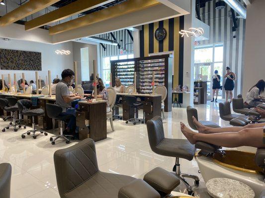 Color selection and nail desk area with face shields between nail artist and customer.