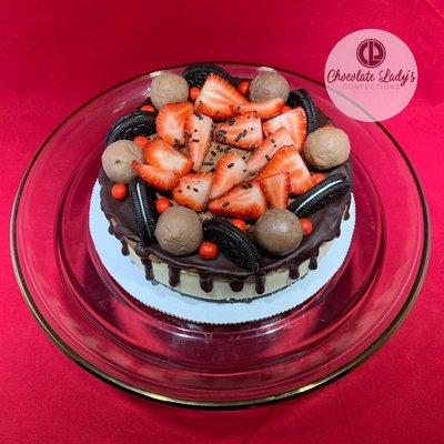 7" cheesecake filled with fresh strawberries, chocolate spheres, Oreo cookies, chocolate curls and a chocolate drip