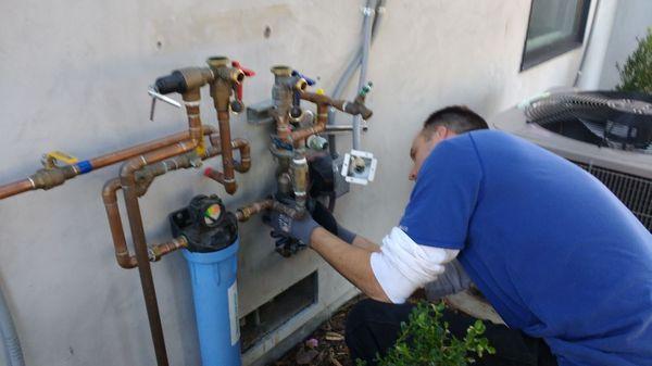 Installing a filter system and flush valves on tankless water heater plumbing on residential property