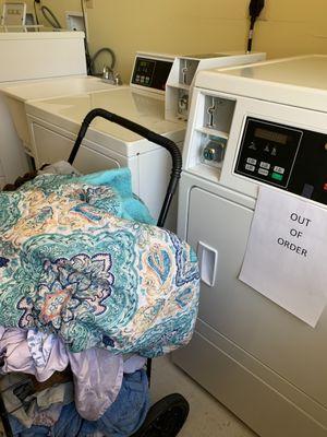 This is a shopping cart on wet clothes next to a dryer with an "out-of-order sign that non-functioning for 4 months.  The