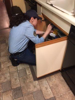 Checking pipes under the sink and looking for leaks.