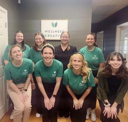 Picture of Wellness Creative staff members in their green company shirts with white logo