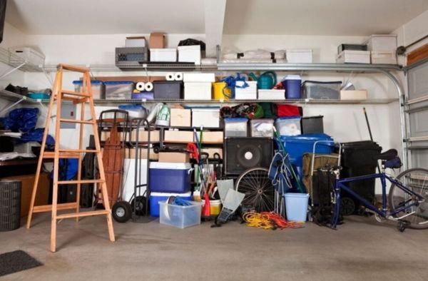 Cluttered home garage full of furniture and unwanted items that need to be decluttered, sorted, organized, and removed from the garage.