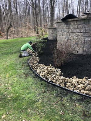 Landscape installation with river cobble around the flowers beds