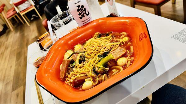 Tomato Broth w/ Oil Noodle, Udon, Soba, Ramen, Luncheon Meat, Spicy Sausage, Broccoli, Napa Cabbage, Spinach, and Quail Egg