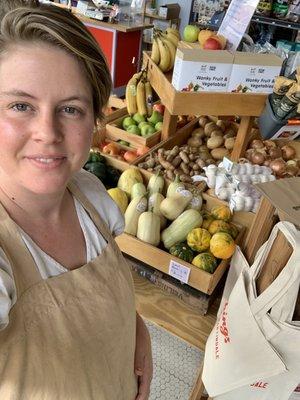 Owner, Taylor Burge, in front of our ever changing local produce stand.