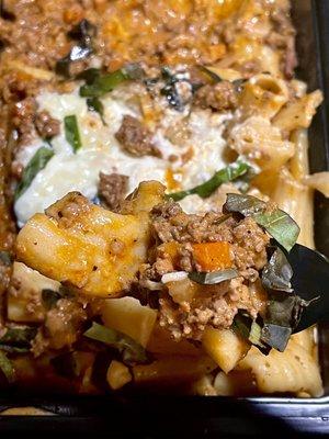 Fresh Rigatoni Bolognese, close up of meat sauce with bits of carrots and slivers of fresh basil