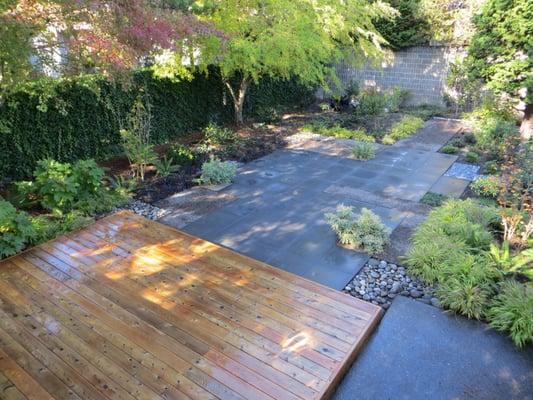 Complete Design/Build: Architectural Slab patio, decorative rock, steel edging, low cedar deck, and plantings.