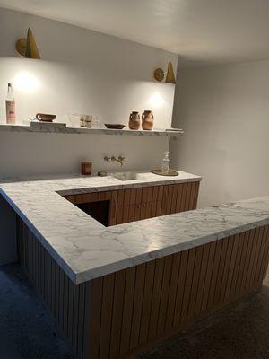 Custom bar installation with solid rift cut white oak.  Wood slats and floating stone shelf.