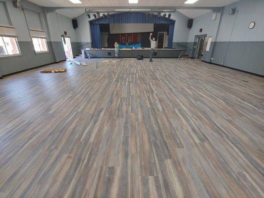 Multi purpose room and stage at local school dine in a commercial vinyl plank floor.