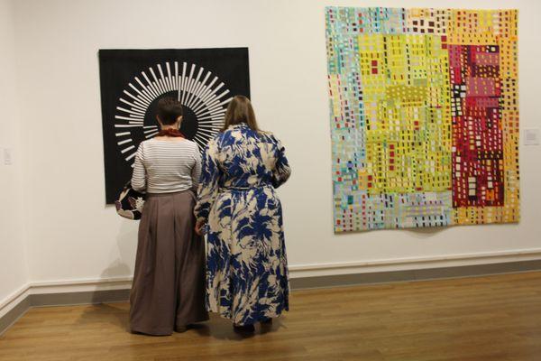 Visitors take a close look at Audrey Esarey's "Repelling Radial," one of 69 pieces in "Quilts=Art=Quilts 2022" at Schweinfurth Art Center.