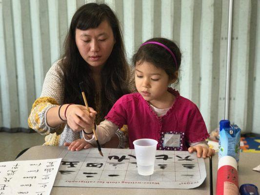 Helping the student writing Chinese characters.  Individual attention in helping with their Chinese calligraphy.