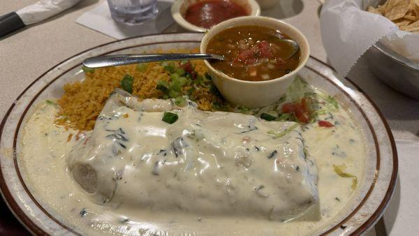 Burrito Alegre covered with queso with borracho beans and rice