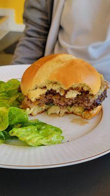 CAFE BURGER: American Wagyu Beef, aged white cheddar, housemade pickles, caramelized onions, Cafe Sauce. Served with a simple salad.