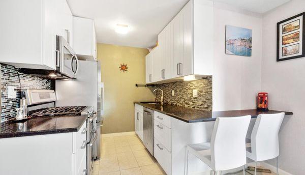 Another angle of the kitchen, which has a wrap around counter top, forming a small breakfast nook.