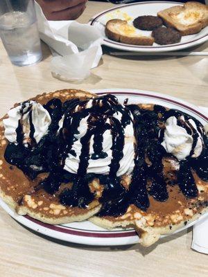 Oreo Pancakes with whipped cream, Oreo cookie crumble, and chocolate drizzle.