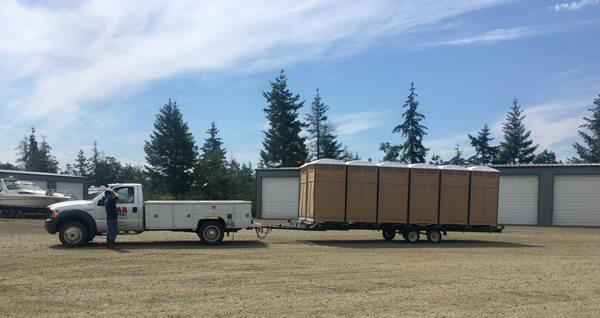 Our service truck pulling new portable restroom units.