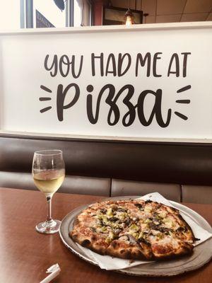 Thin and crispy vegetable pizza with anchovies and a glass of Chardonnay Wine .