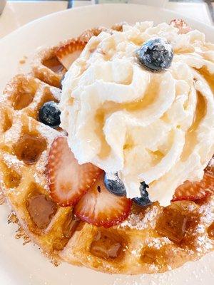 Belgian waffle with fresh strawberries, blueberries, and whipped cream.