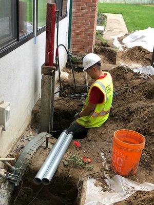 Installing push piers to lift and level a settling home.