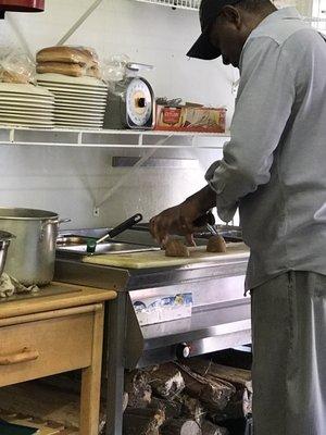 Owner chopping potatoes by hand for French fries.